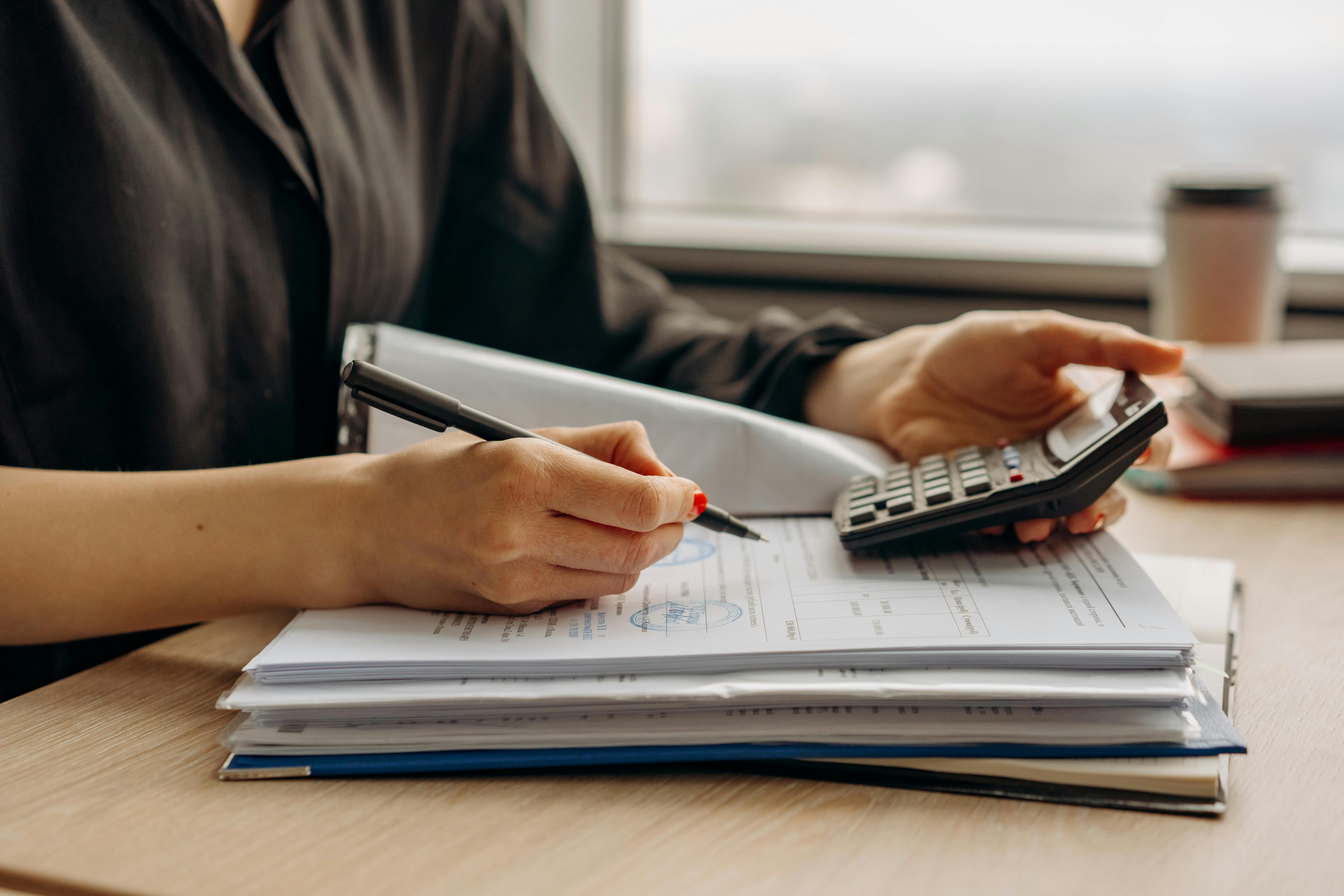 Person in long sleeve shirt holding a pen and calculator