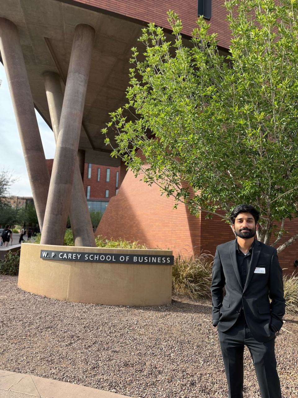 MS-SCM student Karthik Vadlamani in front of a W. P. Carey sign at ASU's Tempe campus