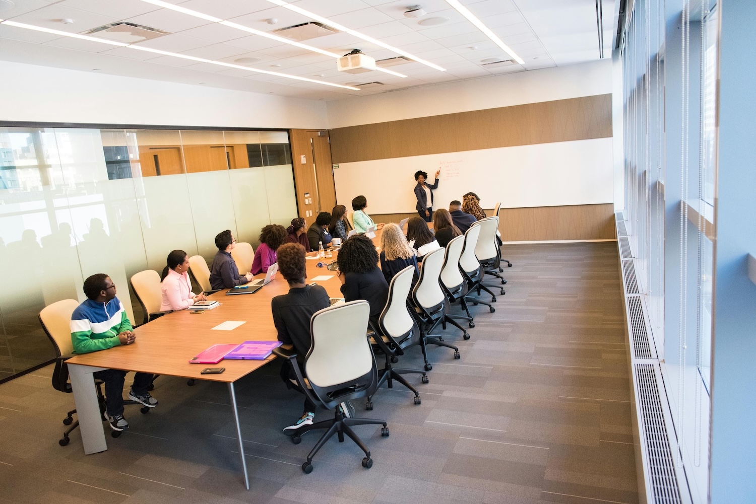 People Sitting on Beige Rolling Chairs on Brown Wooden Boardroom Table Inside Room